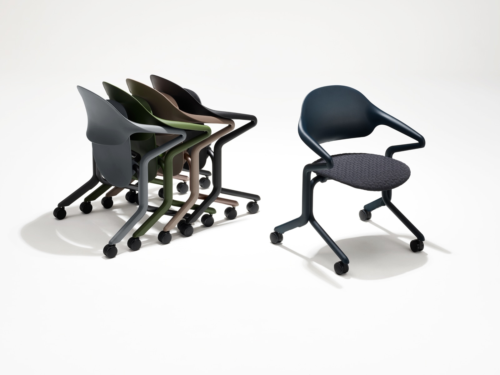 Cuatro sillas nido Fuld en varios colores y acabados anidadas en grupo junto a una única silla nido Fuld en color Nightfall con el textil 3D.